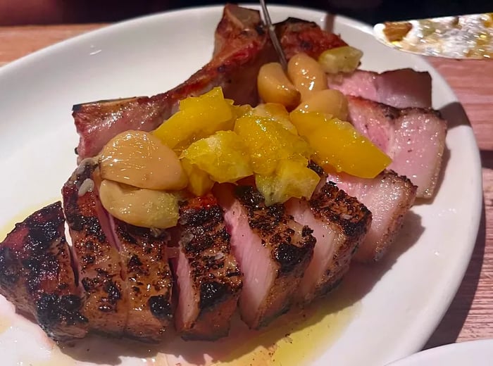 A pork chop adorned with generous pieces of garlic and preserved lemon.