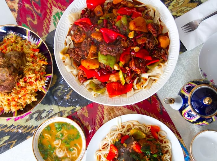 An assortment of dishes including a meat and vegetable platter, rice, noodles, and soup.