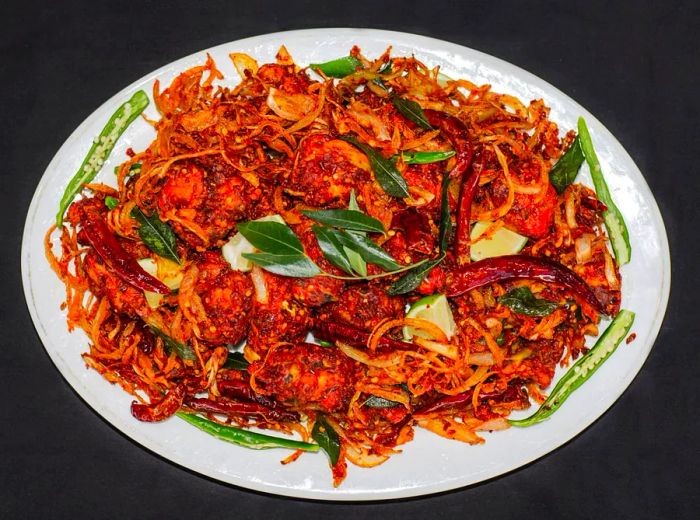 A dark backdrop highlights a plate of spicy fried chicken.