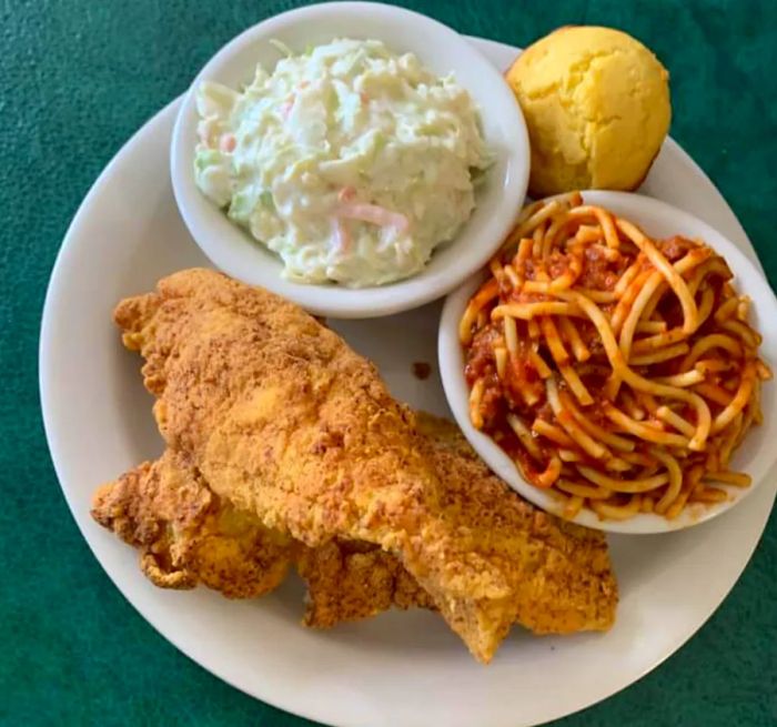 A plate showcases crispy fried chicken legs alongside a generous serving of spaghetti and creamy potato salad.