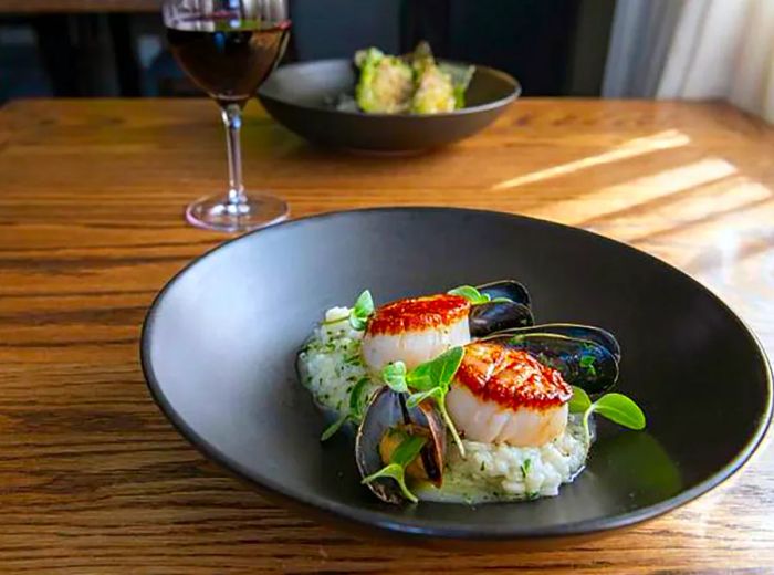 A delightful serving of scallops resting on a bed of fragrant, herby risotto.