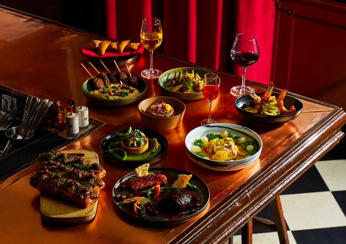 An assortment of dinner plates and glasses of wine arranged on a bar counter.