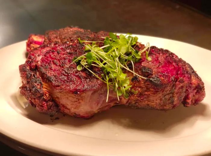 A massive steak on an oval plate, garnished with a sprinkle of herbs.