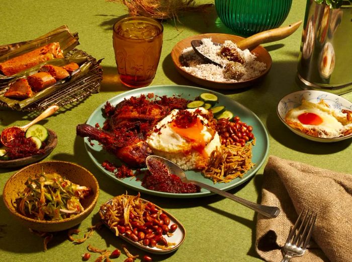 A vibrant nasi lemak plate featuring ayam goreng berempah, surrounded by an array of dishes and beverages.