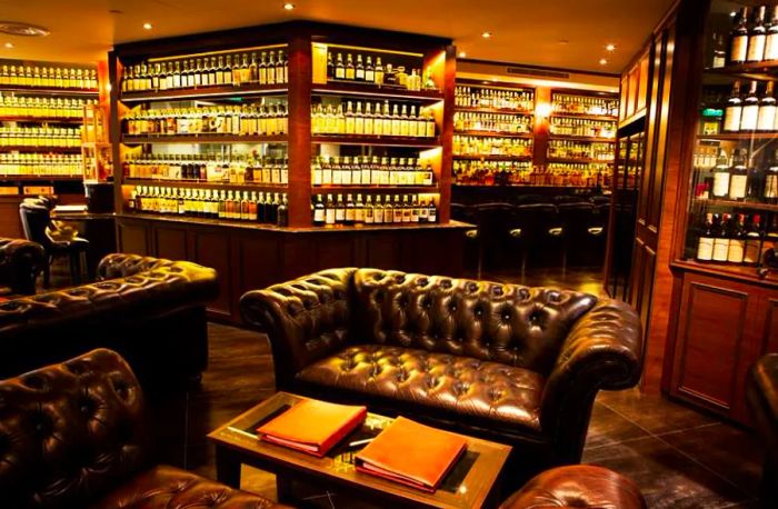 A refined bar room featuring leather sofas and well-stocked shelves of premium spirits.