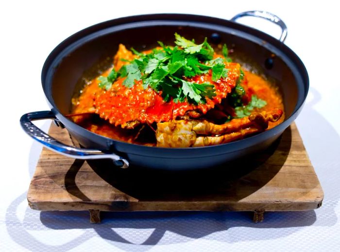 A generous serving of chili crab, elegantly presented in a handled pot.