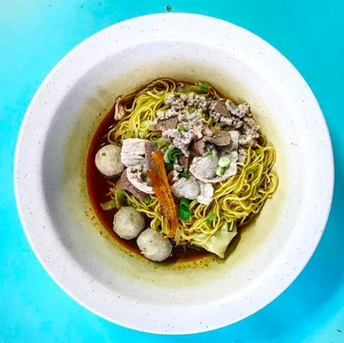 Aerial view of a steaming bowl of pork noodles.