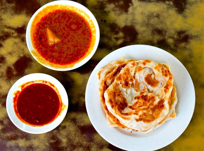 An aerial view of roti prata served with dipping sauces.