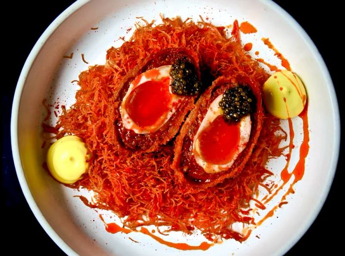 A close-up of deep red scotch eggs served on a bed of noodles.