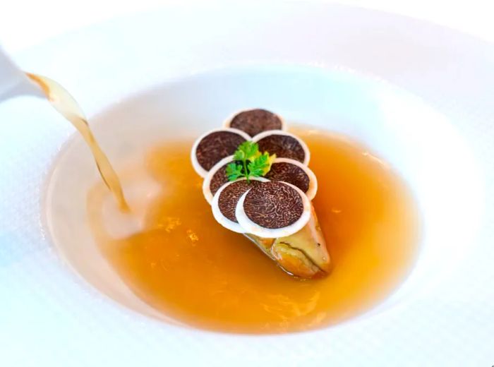 <p>An unseen server delicately pours consommé around a mound of foie gras.</p>