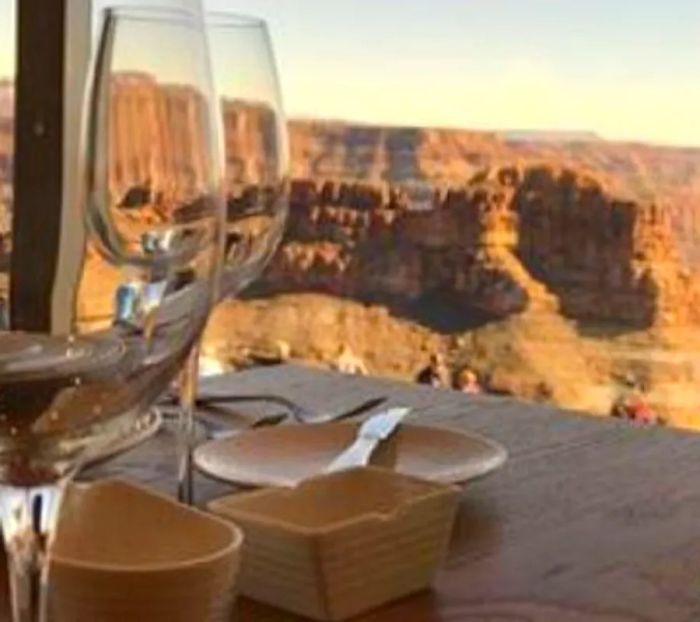 A table set with wine glasses next to a window, offering a stunning view of the Grand Canyon