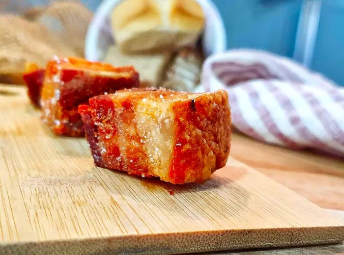 Thick, crispy bacon cubes arranged on a serving board.