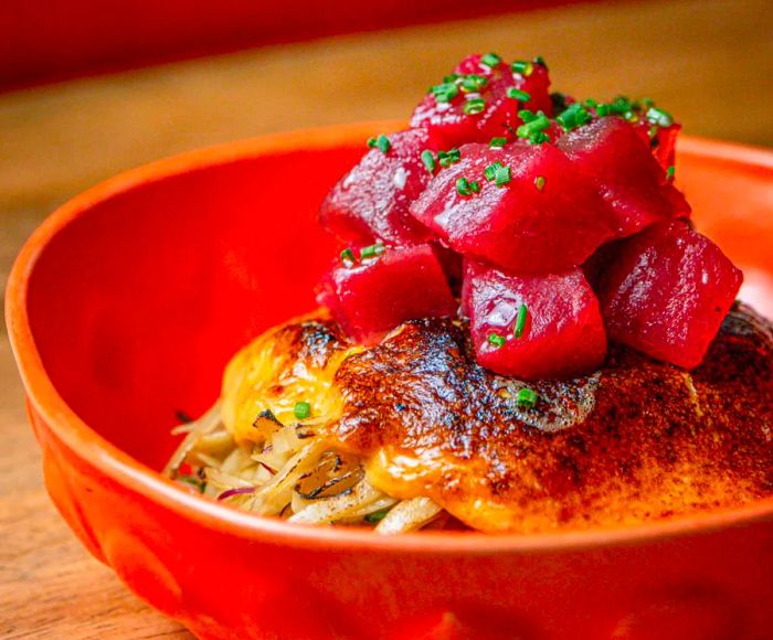 A dish of noodles crowned with a generous layer of golden caramelized mayo and vibrant red tuna cubes.