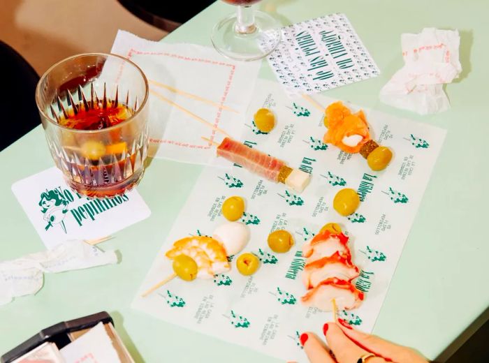 Guests nibble on skewered snacks from branded placemats while sipping glasses of sherry.