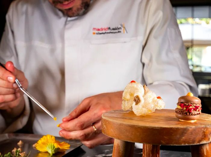 A chef meticulously arranges dishes using tweezers.