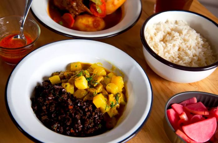 A variety of dishes arranged on a wooden table, illuminated by natural light.