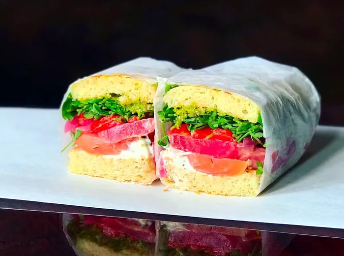 A vegetable sandwich neatly wrapped in wax paper.