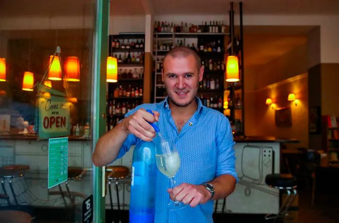 A waiter adds soda water to a glass of white wine at Budapest’s Nappali Kávéház