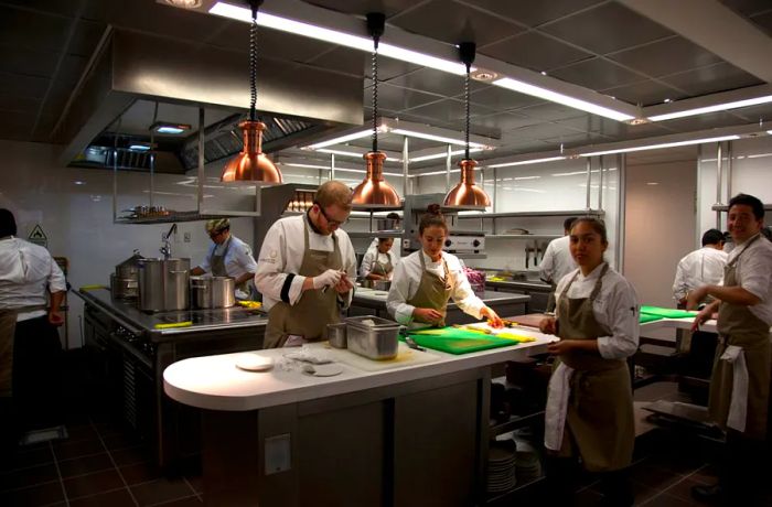 In the restaurant's kitchen, chefs work efficiently at a central island and along stations positioned against the back walls.