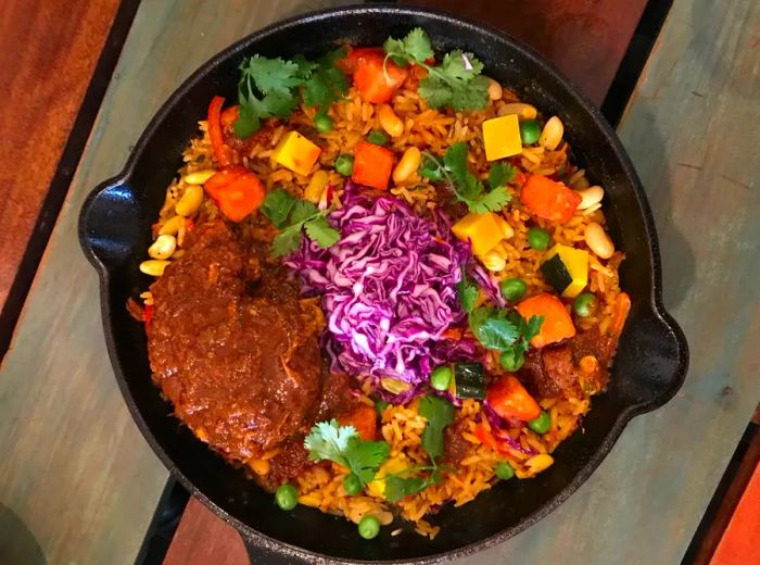 Aerial view of a plate featuring a generous portion of roasted pork, rice, vegetables, and a vibrant mound of sliced cabbage.