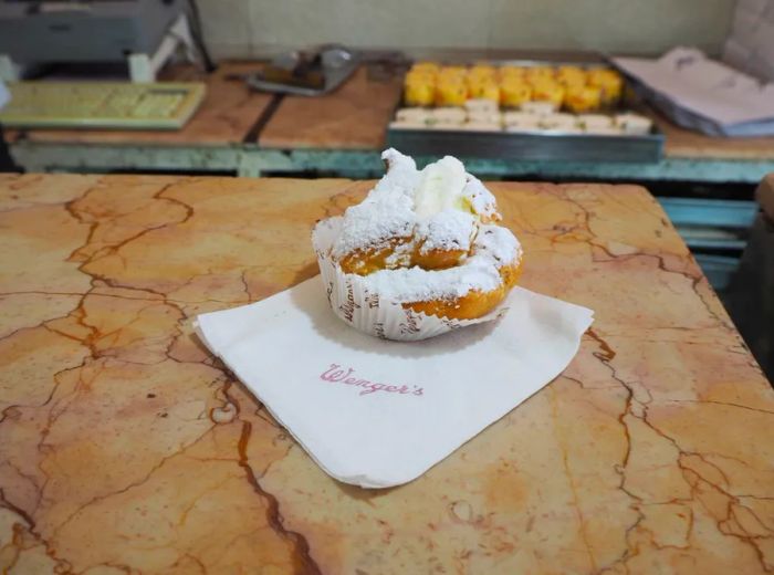 A sugar-coated pastry rests on a napkin atop a marble counter.