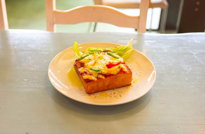 A slice of pizza toast resting on a plate