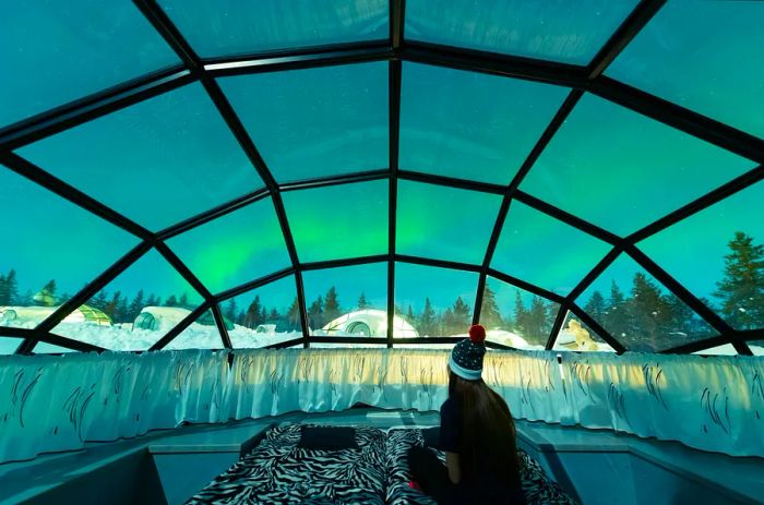 A woman observes the northern lights from within a glass igloo at a resort in Finnish Lapland.