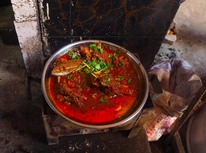 A serving of vibrant meat gravy is presented in a drab, industrial setting.