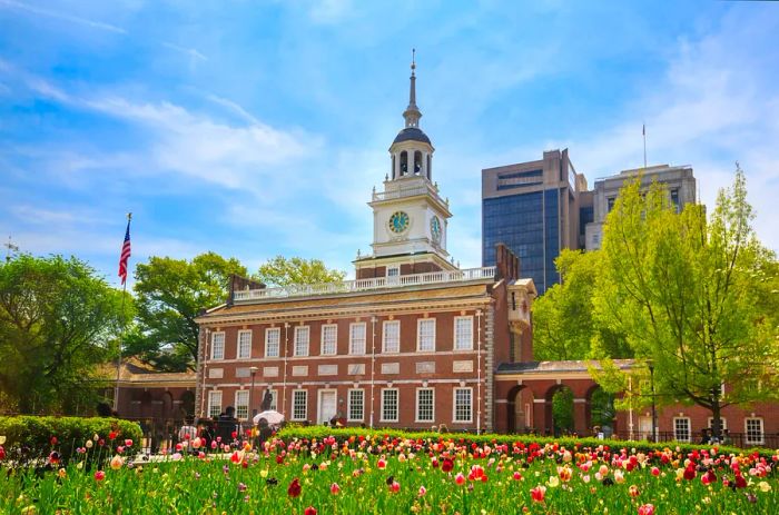 A red-brick structure with a white bell tower set against a tulip garden