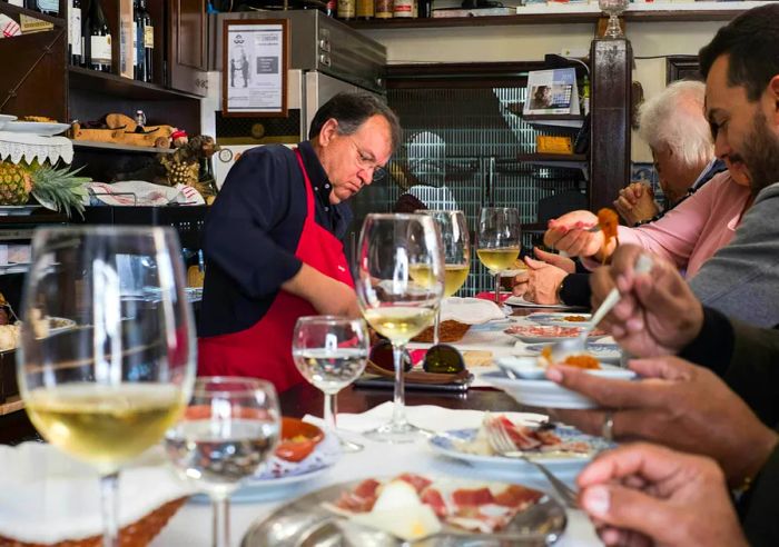 A Portuguese wine bar where a man serves wine and cured meats to patrons.