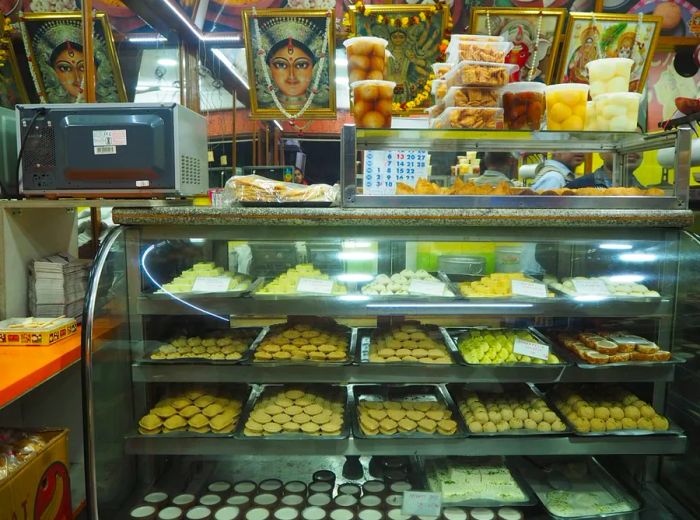 A glass case showcasing an array of small pastries neatly arranged on trays.