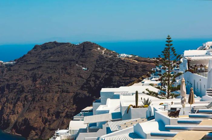 Snow-draped white houses and dramatic mountain vistas under a clear blue sky in Merovigli, Santorini, Greece