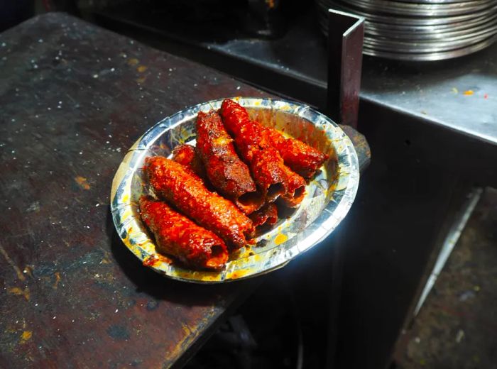 A plate showcasing cylindrical beef kebabs resting on a metal surface.