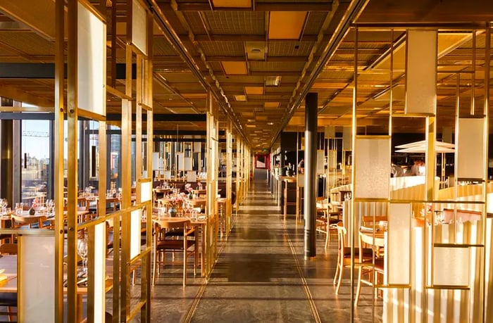 A spacious dining room filled with light, featuring geometric wooden partitions.