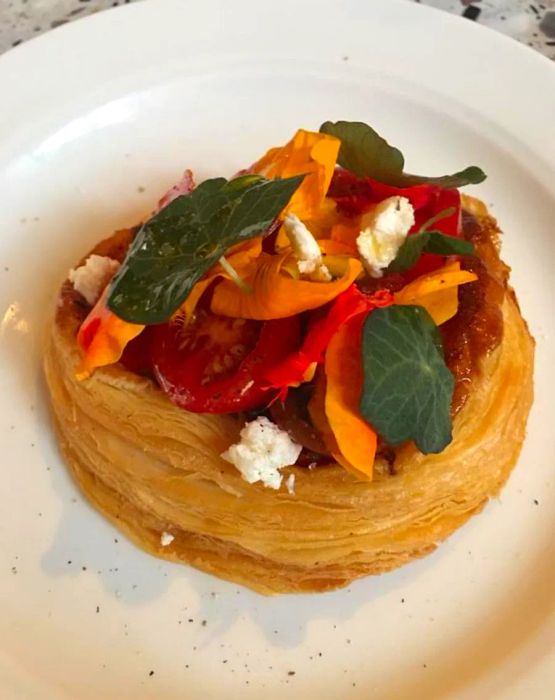 A hearty pastry adorned with tomatoes and aromatic herbs.