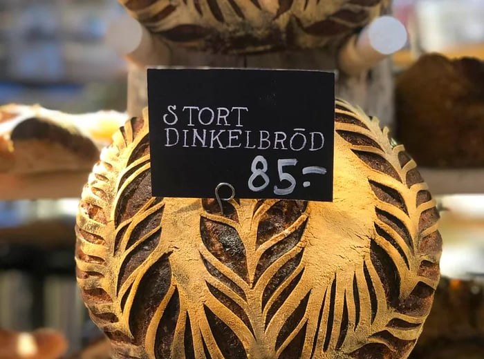 A round loaf of patterned spelt bread labeled in Swedish as “Stort Dinkelbrod” or “large spelt bread,” priced at 85.