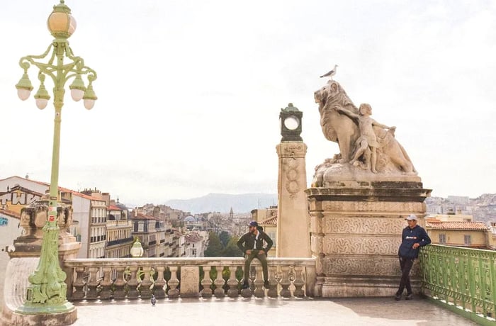 A man perches on a railing overlooking Marseille, France