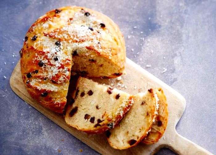 An overhead view of a round loaf of chocolate-studded bread on a cutting board, with a quarter removed and the slices neatly arranged.