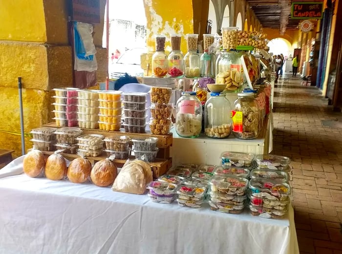 Beneath archways bathed in sunlight, tables are brimming with jars and plastic containers filled with an array of sweets.