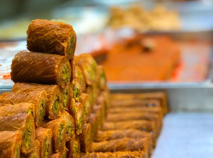 A pyramid of round stuffed pastries stands tall in a display case, with other sweets softly blurred in the background