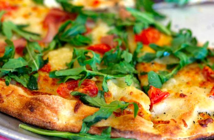 A close-up shot of a pizza adorned with arugula and small slices of pepperoni