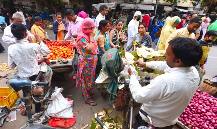 A woman shields her face while purchasing fruits and vegetables from a street vendor