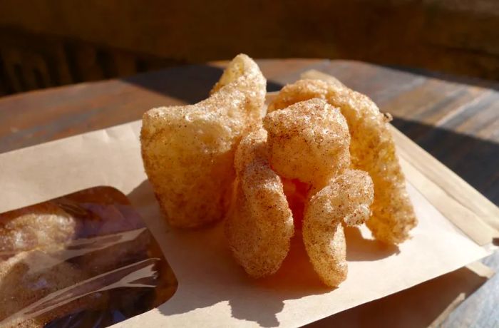 A handful of fluffy pork rinds resting on the brown paper they come in