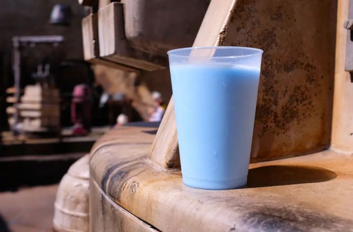 A vibrant glass of blue milk rests on the interstellar backdrop of Galaxy’s Edge in the Star Wars park