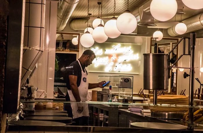 A chef checks their phone in a Paris restaurant kitchen at night.