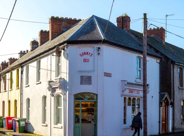 The entrance to Sonny’s Deli features a classic Georgian-style building with a simple white facade and a steep roof, showcasing the restaurant's name in bold red letters above the door.