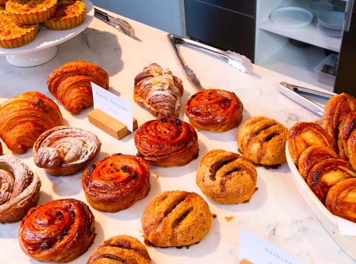 A vibrant counter showcasing an assortment of rolls, croissants, pies, and other delectable pastries.