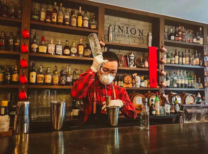 A bartender wearing a medical face mask serves a drink behind the bar in Shanghai.