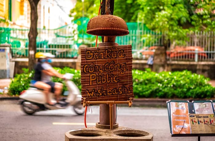 A temporary bamboo public washbasin with a sign on the street.