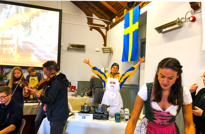 A woman raises her arms amidst a gathering of porridge enthusiasts.